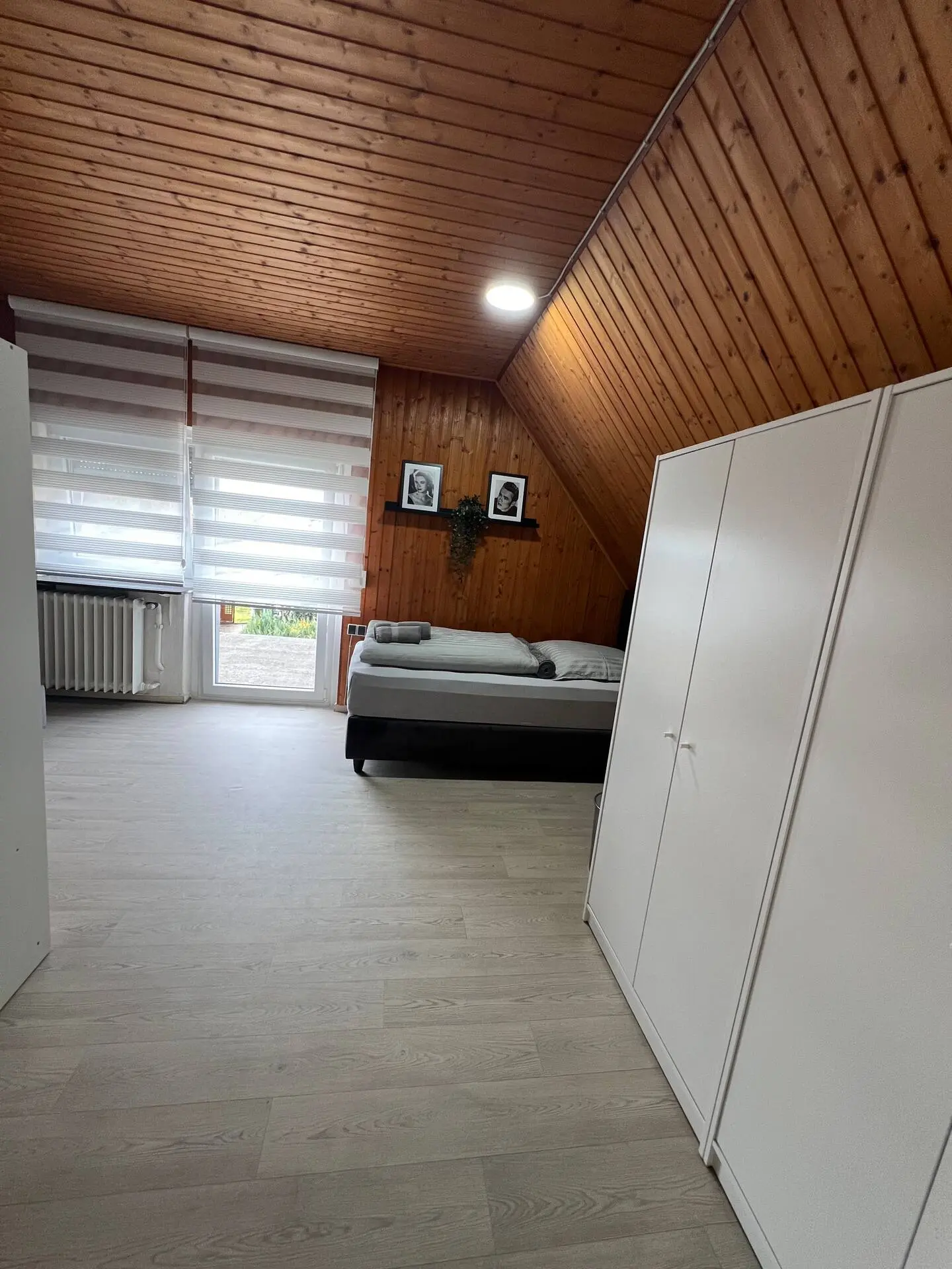 Weiteres Dachgeschosszimmer mit Bett, Holzdecke und Balkontür