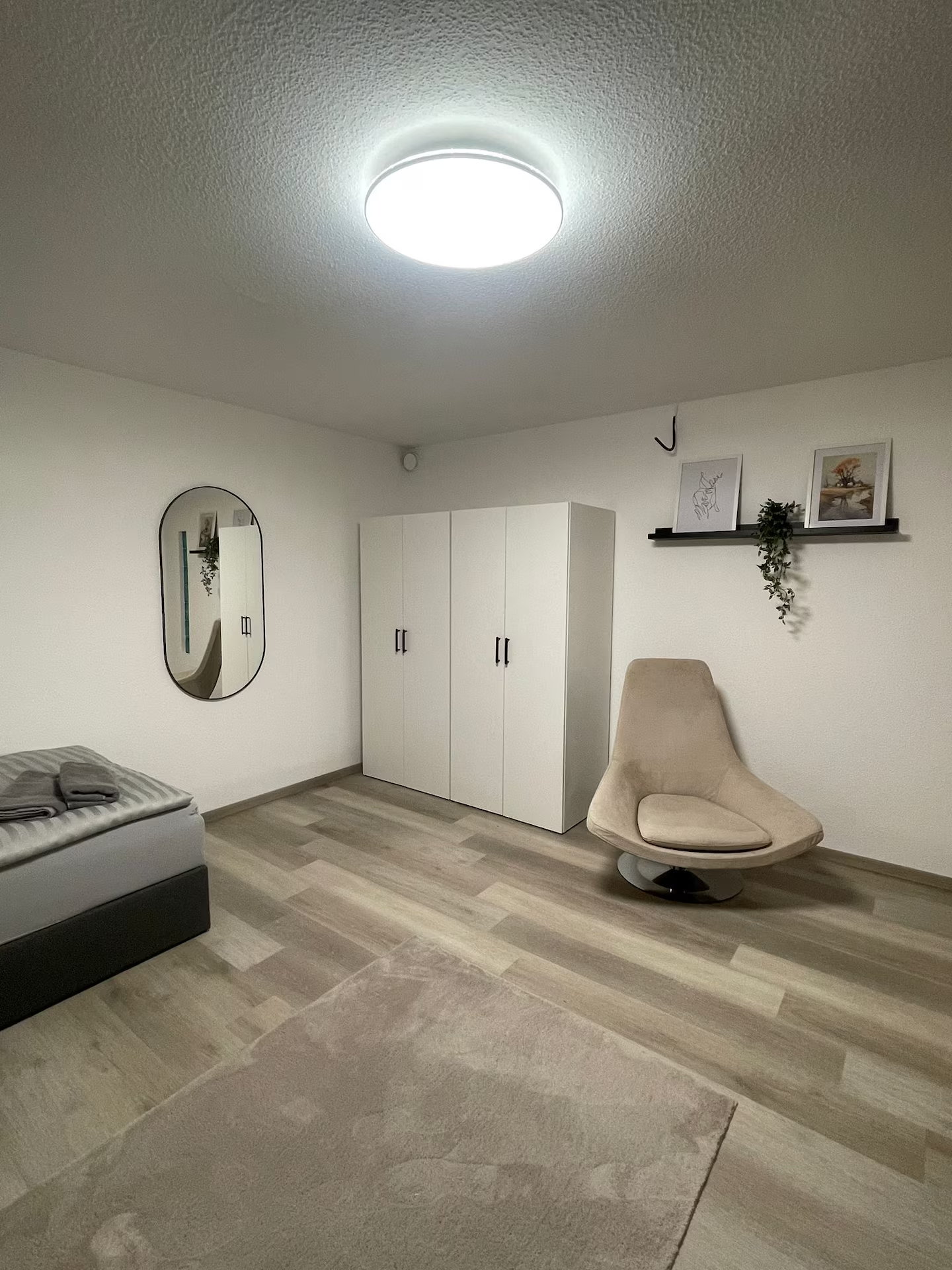 Schlafraum mit Kleiderschrank, Spiegel und Sessel