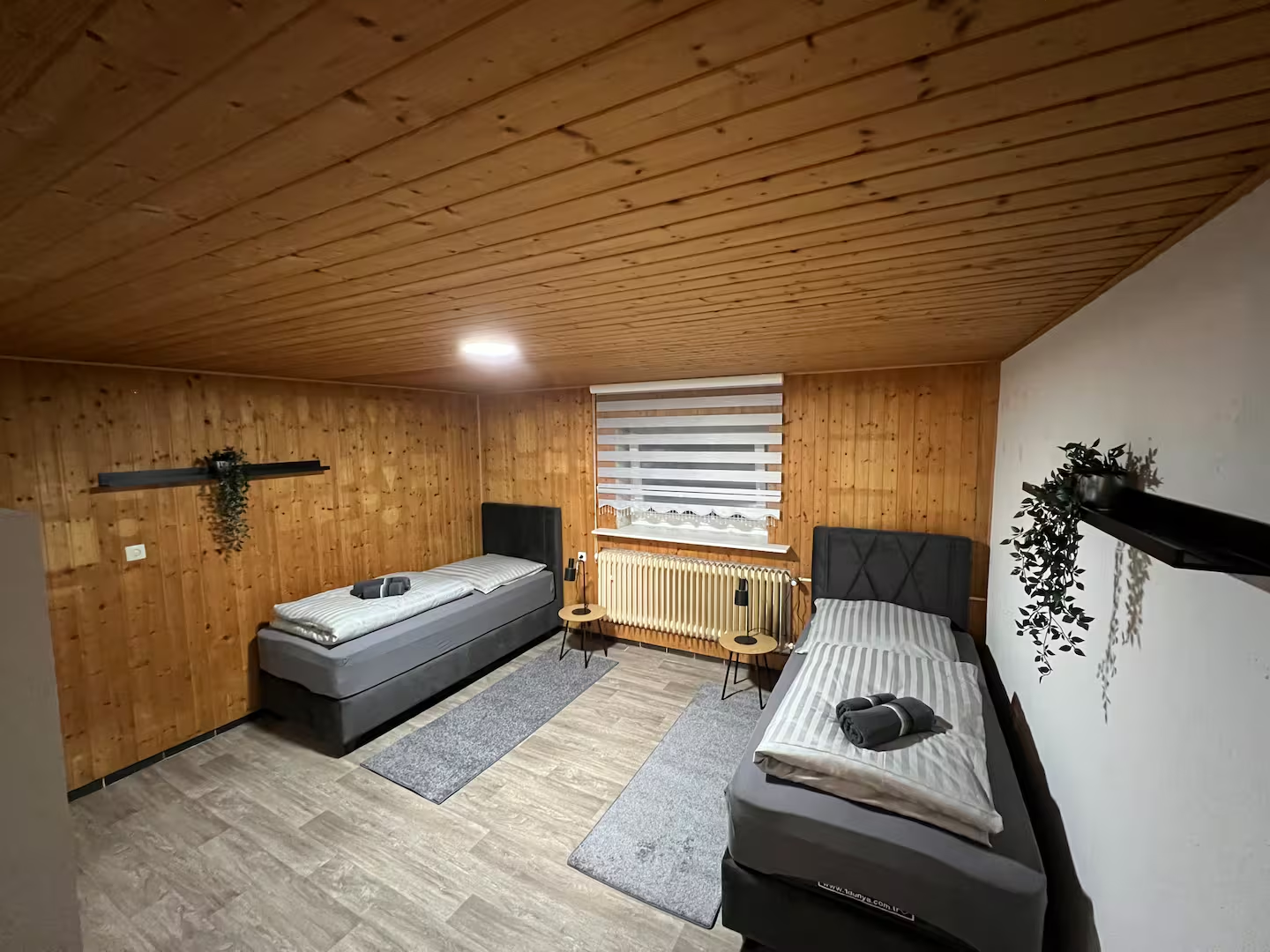 Schlafzimmer mit zwei Einzelbetten, Holzvertäfelung und Leselampen