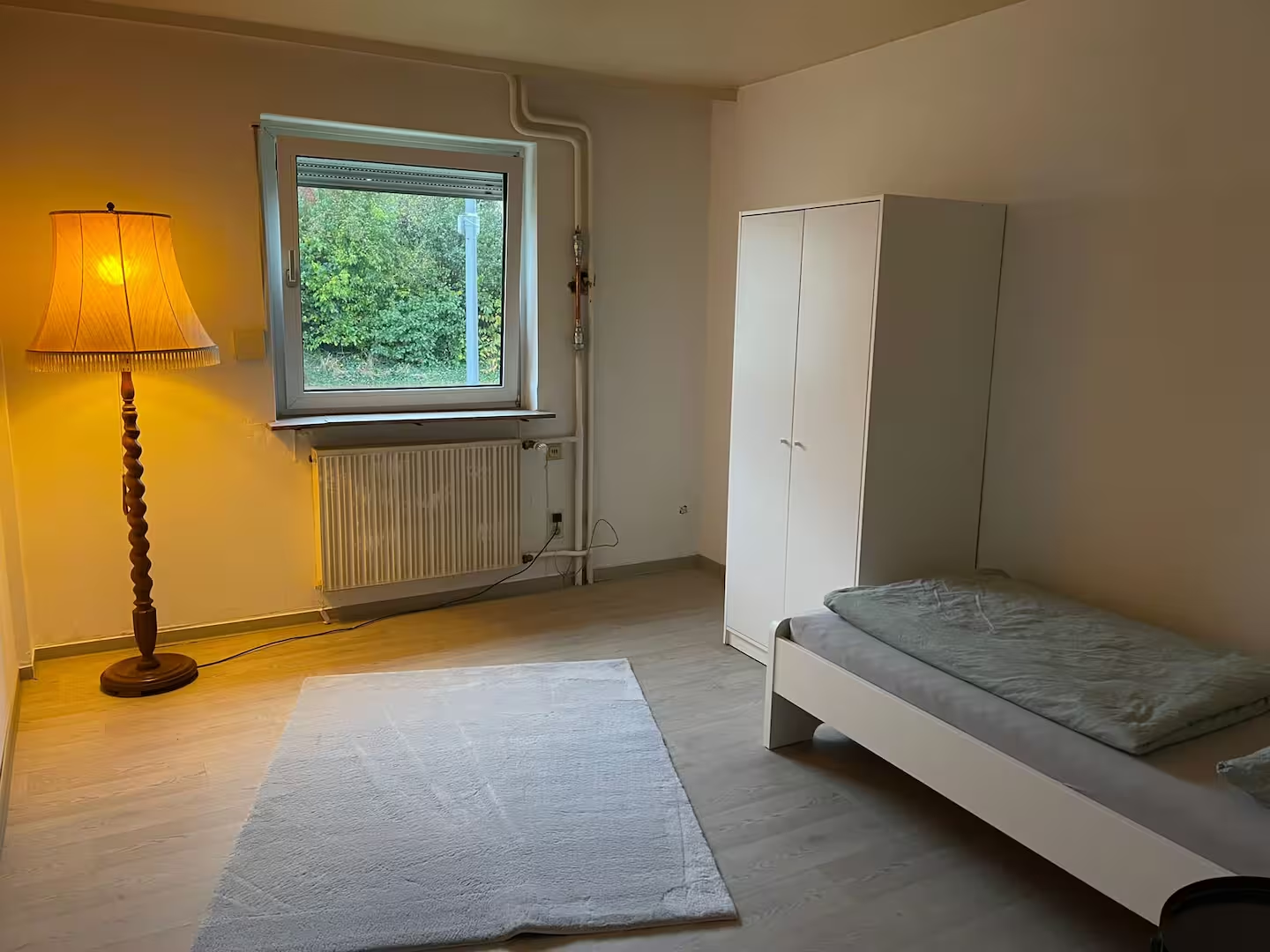 Großzügiges Einzelzimmer mit Fenster und Stehleuchte